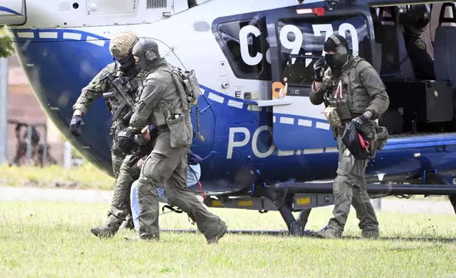 The alleged perpetrator of the knife attack in Solingen is escorted from a helicopter in Karlsruhe, Germany, Sunday, Aug. 25, 2024. German police say a 26-year-old man has turned himself in, saying he was responsible for the deadly Solingen knife attack that left three dead and eight wounded at a festival marking the city’s 650th anniversary. (Uli Deck/dpa via AP)