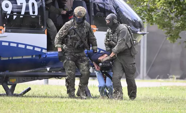 The alleged perpetrator of the knife attack in Solingen is escorted from a helicopter in Karlsruhe, Germany, Sunday, Aug. 25, 2024. German police say a 26-year-old man has turned himself in, saying he was responsible for the deadly Solingen knife attack that left three dead and eight wounded at a festival marking the city’s 650th anniversary. (Uli Deck/dpa via AP)