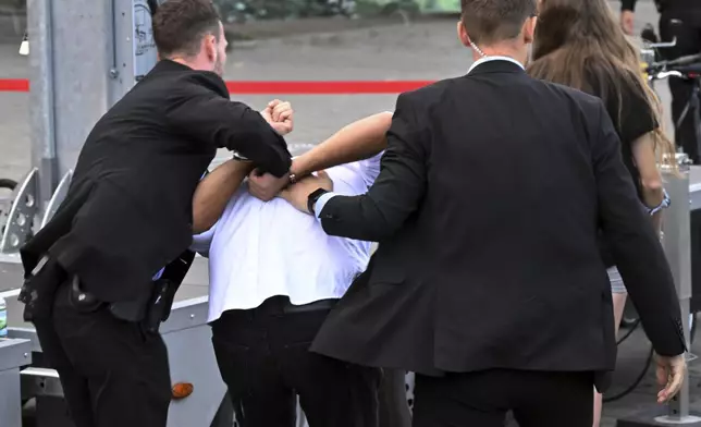 Bodyguards take away a man who allegedly carried out an attack with red paint at an election campaign event organized by the Sahra Wagenknecht Alliance (BSW) on Cathedral Square, in Erfurt, Germany, Thursday Aug. 29, 2024. (Martin Schutt/dpa via AP)