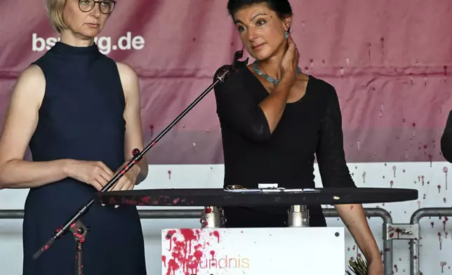 Sahra Wagenknecht, right, chairwoman of the Sahra Wagenknecht Alliance (BSW), and Katja Wolf, Thuringian BSW state chairwoman and top candidate for the 2024 state election in Thuringia, stand on stage after an attack with red paint at the election campaign event on Domplatz, Erfurt, Germany, Thursday Aug. 29, 2024. (Martin Schutt/dpa via AP)