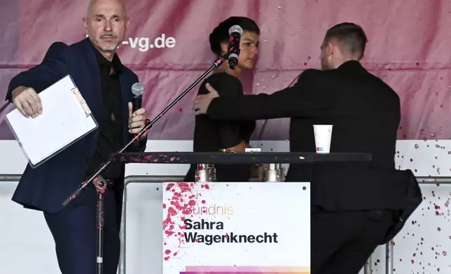 Sahra Wagenknecht, Chairwoman of the Sahra Wagenknecht Alliance (BSW), is escorted off the stage by a bodyguard following an attack with red paint during the election campaign event on Domplatz, Erfurt, Germany, Thursday Aug. 29, 2024. (Martin Schutt/dpa via AP)