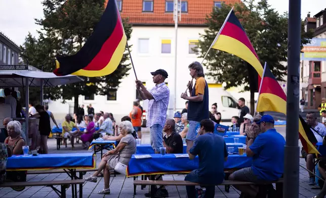 Supporters of the far-right Alternative for Germany party, or AfD, hold German national flags as they attend an election campaign rally of the party for upcoming state elections, in Suhl, Germany, Tuesday, Aug. 13, 2024. In the federal state Thuringia, in former East Germany, the citizens are called to vote for a new state parliament on Sept. 1, 2024. (AP Photo/Markus Schreiber)