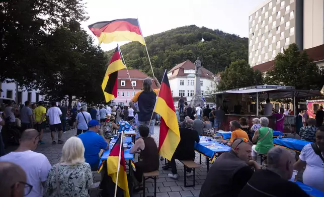 People wave German national flags as they listen to Bjoern Hoecke, top candidate of the far-right Alternative for Germany party, or AfD, during an election campaign rally of the party for upcoming state elections in Suhl, Germany, Tuesday, Aug. 13, 2024. (AP Photo/Markus Schreiber)