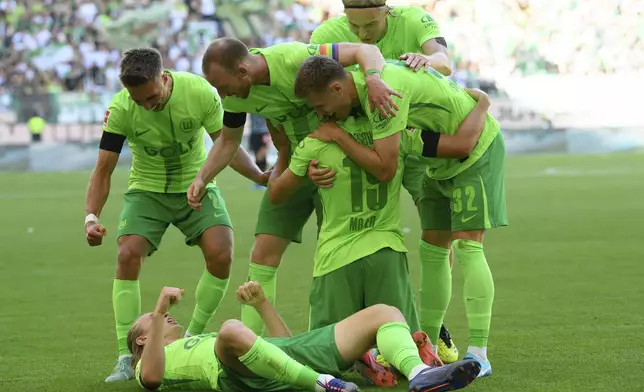 Wolfsburg's Lovro Majer, center kneeling, celebrates with teammates after scoring his side's second goal of the game during the German Bundesliga soccer match between VfL Wolfsburg and FC Bayern Munich at the Volkswagen Arena in Wolfsburg, Germany, Sunday, Aug. 27, 2024. (Swen Pfoertner/dpa via AP)