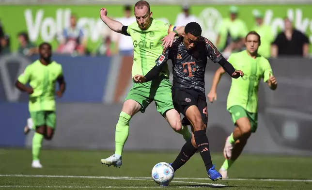 Bayern's Jamal Musiala, second right, in action against Wolfsburg's Maximilian Arnold during the German Bundesliga soccer match between VfL Wolfsburg and FC Bayern Munich at the Volkswagen Arena in Wolfsburg, Germany, Sunday, Aug. 27, 2024. (Swen Pfoertner/dpa via AP)