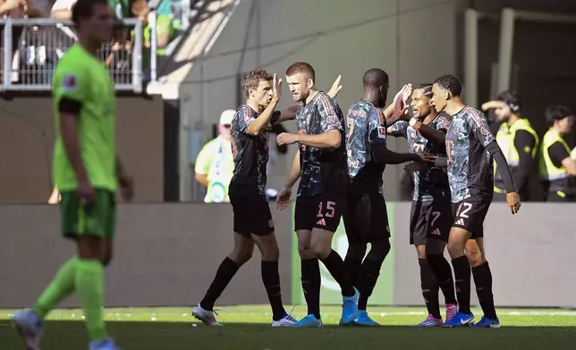 Bayern's Serge Gnabry, second right, celebrates with his teammates after scoring his side's third goal of the game during the German Bundesliga soccer match between VfL Wolfsburg and FC Bayern Munich at the Volkswagen Arena in Wolfsburg, Germany, Sunday, Aug. 27, 2024. (Swen Pfoertner/dpa via AP)