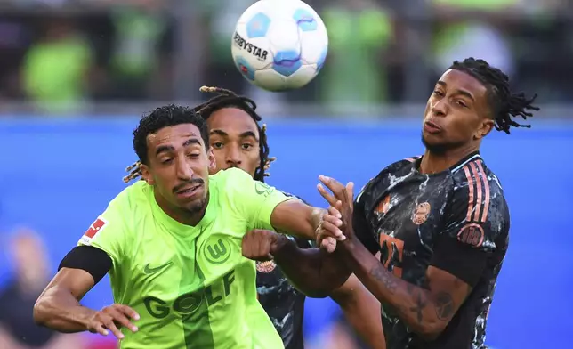 Wolfsburg's Tiago Tomas, left, in action against Bayern's Michael Olise during the German Bundesliga soccer match between VfL Wolfsburg and FC Bayern Munich at the Volkswagen Arena in Wolfsburg, Germany, Sunday, Aug. 27, 2024. (Swen Pfoertner/dpa via AP)