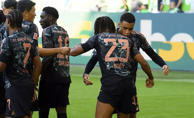 Bayern's Jamal Musiala, right, celebrates scoring his side's first goal of the game with teammate Sacha Boey, who provided the assist, during the German Bundesliga soccer match between VfL Wolfsburg and FC Bayern Munich at the Volkswagen Arena in Wolfsburg, Germany, Sunday, Aug. 27, 2024. (Swen Pfoertner/dpa via AP)