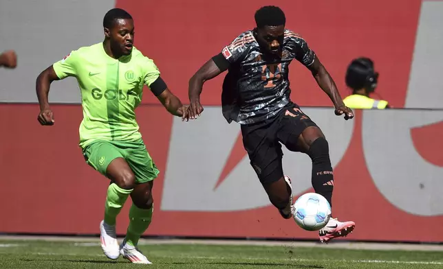 Wolfsburg's Ridle Baku, left, in action against Bayern's Alphonso Davies during the German Bundesliga soccer match between VfL Wolfsburg and FC Bayern Munich at the Volkswagen Arena in Wolfsburg, Germany, Sunday, Aug. 27, 2024. (Swen Pfoertner/dpa via AP)