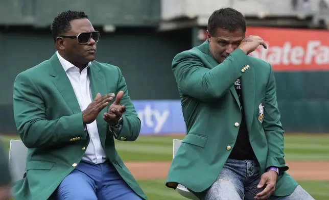 Former baseball player Jose Canseco, right, wipes away tears after being being inducted into the Oakland Athletics' Hall of Fame before a baseball game against the San Francisco Giants, Saturday, Aug. 17, 2024, in Oakland, Calif. Miguel Tejada, left, was also inducted. (AP Photo/Godofredo A. Vásquez)