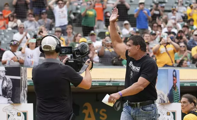 Former baseball player Jose Canseco, right, waves to the crowd while being introduced during an Oakland Athletics' Hall of Fame ceremony before a baseball game against the San Francisco Giants, Saturday, Aug. 17, 2024, in Oakland, Calif. (AP Photo/Godofredo A. Vásquez)