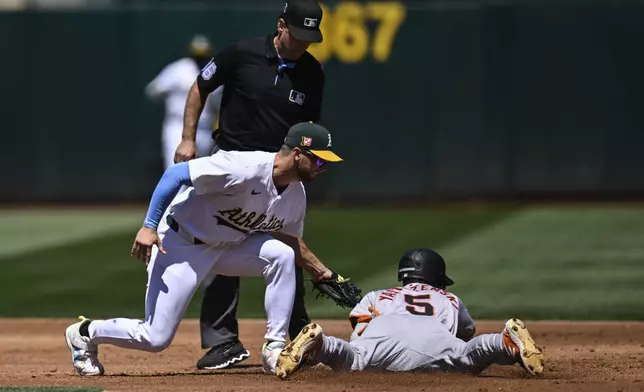 San Francisco Giants' Mike Yastrzemski (5) is tagged out by Oakland Athletics shortstop Max Schuemann, front left, while attempting to steal second base during the third inning of a baseball game Sunday, Aug. 18, 2024, in Oakland, Calif. (AP Photo/Eakin Howard)