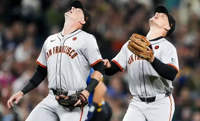 San Francisco Giants shortstop Tyler Fitzgerald, left, and third baseman Matt Chapman, right, look to catch a pop fly off the bat of Seattle Mariners' Randy Arozarena during the third inning of a baseball game, Friday, Aug. 23, 2024, in Seattle. (AP Photo/Lindsey Wasson)