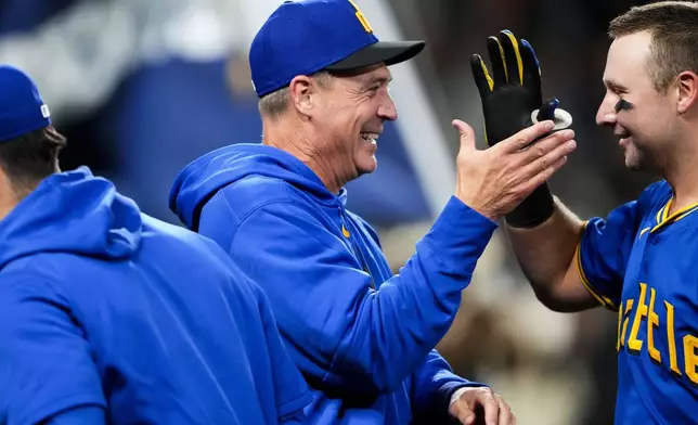 Seattle Mariners manager Dan Wilson, center, greets catcher Cal Raleigh as they celebrate a 6-5 win over the San Francisco Giants in 10 innings after a baseball game, Friday, Aug. 23, 2024, in Seattle. (AP Photo/Lindsey Wasson)