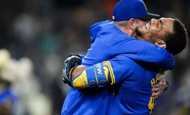 Seattle Mariners manager Dan Wilson, left, is hugged by Julio Rodríguez as they celebrate beating the San Francisco Giants 6-5 in 10 innings after a baseball game, Friday, Aug. 23, 2024, in Seattle. (AP Photo/Lindsey Wasson)