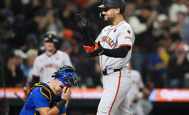 San Francisco Giants' Michael Conforto, right, reacts as he crosses home after hitting a two-run home run as Seattle Mariners catcher Cal Raleigh wipes his eyes during the fourth inning of a baseball game Friday, Aug. 23, 2024, in Seattle. (AP Photo/Lindsey Wasson)