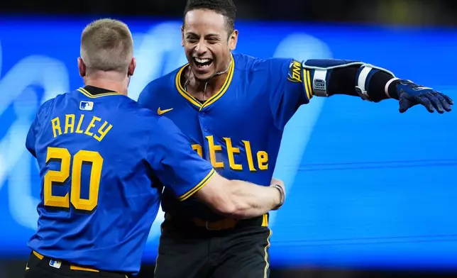 Seattle Mariners' Leo Rivas, right, is greeted by teammate Luke Raley (20) after hitting a game-winning single against the San Francisco Giants during the 10th inning of a baseball game, Friday, Aug. 23, 2024, in Seattle. The Mariners won 6-5. (AP Photo/Lindsey Wasson)