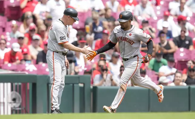 San Francisco Giants' LaMonte Wade Jr., right, celebrates with third base coach Matt Williams, left, as he rounds the bases after hitting a solo home run during the sixth inning of a baseball game against the Cincinnati Reds, Sunday, Aug. 4, 2024, in Cincinnati. (AP Photo/Jeff Dean)