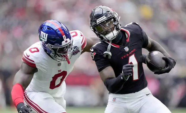 Houston Texans wide receiver Stefon Diggs (1) picks up a first down before being stopped by New York Giants linebacker Brian Burns (0) in the first half of a preseason NFL football game, Saturday, Aug. 17, 2024, in Houston. (AP Photo/Eric Gay)