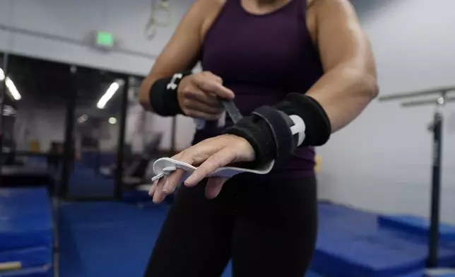 Angela Fuller, 44, puts on grips as she trains, Wednesday, July 24, 2024 in Littleton, Colo. (AP Photo/Brittany Peterson)