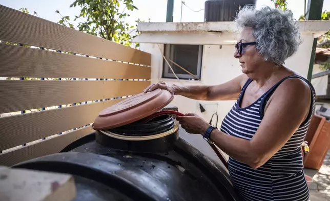 Haroula Psaropoulou, checks the level inside a water tank, in the village of Nea Potidea, at Halkidiki peninsula, northern Greece, Aug. 19, 2024. A severe drought in northern Greece, worsened by successive heatwaves and low rainfall, is causing water shortages that are threatening agriculture, drying up lakes, and stressing local communities dependent on tourism. (AP Photo/Giannis Papanikos)