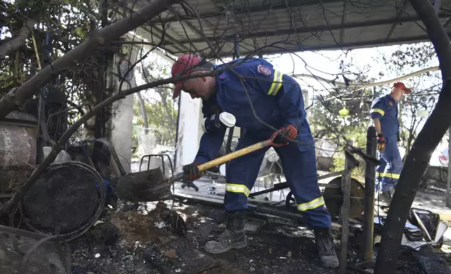 Firefighters work outside a damage house in Chalandri suburb of Athens, on Tuesday, Aug. 13, 2024, following a major wildfire that has burned into the northern suburbs of the Greek capital, triggered multiple evacuations. (AP Photo/Michael Varaklas)