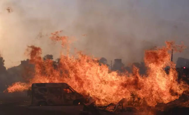 The fire burns a vehicle during a fire in northern Athens, Monday, Aug. 12, 2024, as hundreds of firefighters tackle a major wildfire raging out of control on fringes of Greek capital. (AP Photo/Aggelos Barai)