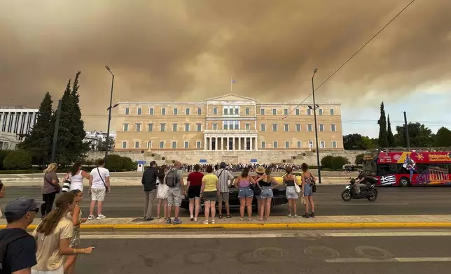 Smoke from wildfires is seen above the Greek parliament building in central Athens, Sunday, Aug. 11, 2024, after a blaze northeast of the capital forced evacuations in the area. (AP Photo/Derek Gatopoulos)