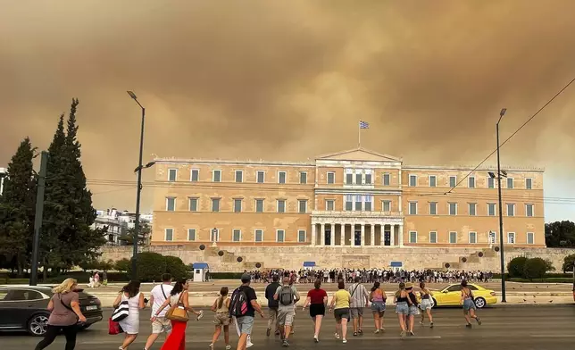 Smoke from wildfires is seen above the Greek parliament building in central Athens, Sunday, Aug. 11, 2024, after a blaze northeast of the capital forced evacuations in the area. (AP Photo/Derek Gatopoulos)