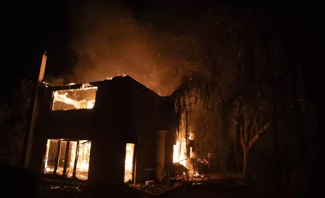 A house burns in Varnava village during a wildfire, north of Athens, Greece, Sunday, Aug. 11, 2024. Many regions of the country are on high alert due to high temperatures and winds. (AP Photo/Michael Varaklas)