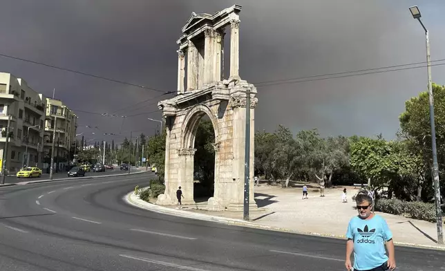 Smoke from wildfires is seen above the Hadrian's Arch in central Athens, Sunday, Aug. 11, 2024, after a blaze northeast of the capital forced evacuations in the area. (AP Photo/Derek Gatopoulos)