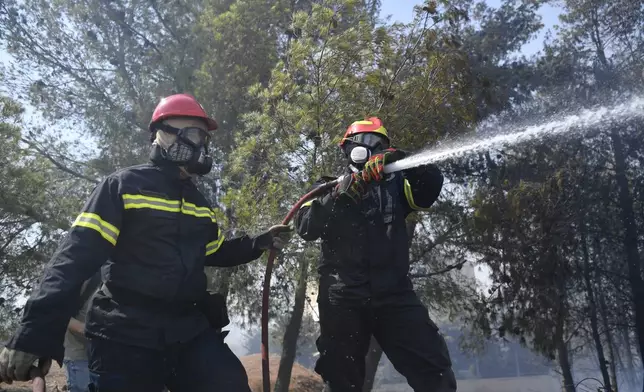 Firefighters operate in Dioni, northeast of Athens, Greece, Monday, Aug. 12, 2024. Hundreds of firefighters backed by dozens of water-dropping planes and helicopters were battling the flames from first light Monday, with a major forest fire that began the previous day raging out of control on the fringes of Athens, fanned by strong winds. (AP Photo/Michael Varaklas)