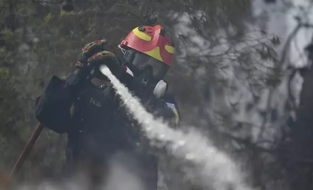 A firefighter operates in Dioni, northeast of Athens, Greece, Monday, Aug. 12, 2024. Hundreds of firefighters backed by dozens of water-dropping planes and helicopters were battling the flames from first light Monday, with a major forest fire that began the previous day raging out of control on the fringes of Athens, fanned by strong winds. (AP Photo/Michael Varaklas)