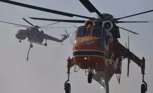 Two firefighting helicopters operate near Penteli, northeast of Athens, Greece, Monday, Aug. 12, 2024. Hundreds of firefighters backed by dozens of water-dropping planes and helicopters were battling the flames from first light Monday, with a major forest fire that began the previous day raging out of control on the fringes of Athens, fanned by strong winds. (AP Photo/Michael Varaklas)