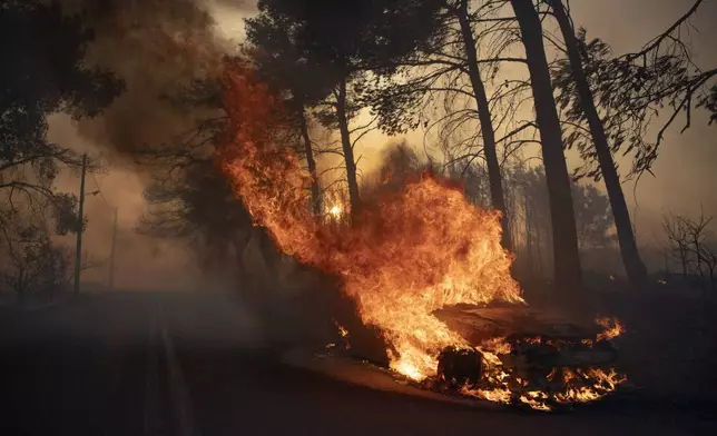 A car burns in Varnava village during a wildfire, north of Athens, Greece, Sunday, Aug. 11, 2024, with many regions of the country on high alert due to high temperatures and wind speeds. (AP Photo/Michael Varaklas)