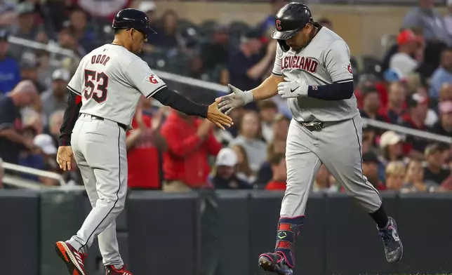 Cleveland Guardians' Josh Naylor celebrates after his three-run home run with third base coach Rouglas Odor as he runs the bases during the fifth inning of the second game of a baseball doubleheader against the Minnesota Twins, Friday, Aug. 9, 2024, in Minneapolis. (AP Photo/Matt Krohn)