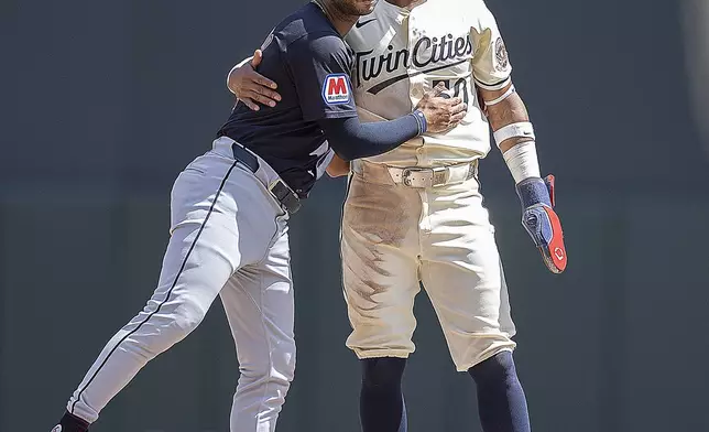 Minnesota Twins' Willi Castro (50), right, gets a hug from Cleveland Guardians shortstop Brayan Rocchio (4) after the call at second was challenged by the Twins in the bottom of the fifth inning of a baseball game in Minneapolis, Minn., Sunday, Aug. 11, 2024. (Elizabeth Flores/Star Tribune via AP)