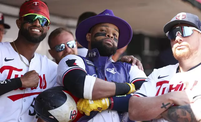 Minnesota Twins' Carlos Santana, center, celebrates his solo home run with teammates Willi Castro, left, and Christian Vázquez, right, in the dugout during the second inning of the first game of a baseball doubleheader against the Cleveland Guardians, Friday, Aug. 9, 2024, in Minneapolis. (AP Photo/Matt Krohn)