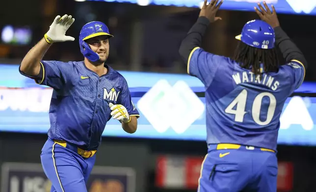 Minnesota Twins' Matt Wallner, left, celebrates after his three-run home run with third base coach Tommy Watkins, right, during the fifth inning of the second game of a baseball doubleheader against the Cleveland Guardians, Friday, Aug. 9, 2024, in Minneapolis. (AP Photo/Matt Krohn)