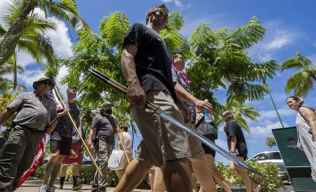 Members of Hawaii Firearms Coalition walk around Waikiki with their non-firearm weapons on Saturday, June 22, 2024, in Honolulu, Hawaii. (AP Photo/Mengshin Lin)