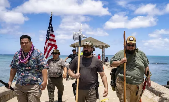 Members of Hawaii Firearms Coalition walk around Waikiki with their non-firearm weapons on Saturday, June 22, 2024, in Honolulu, Hawaii. (AP Photo/Mengshin Lin)