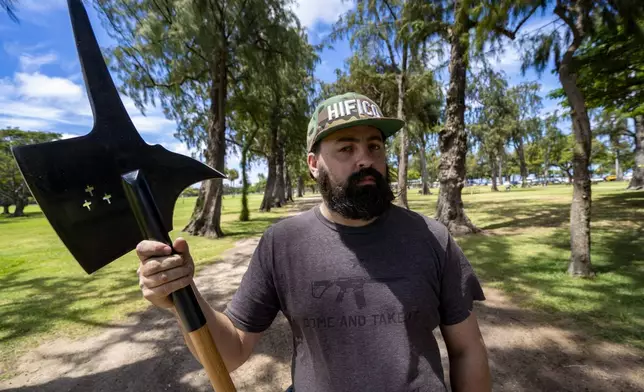 Andrew Roberts, director of the Hawaii Firearms Coalition, poses for a portrait with his halberd while talking to a Honolulu police officer at Kapiolani Park on Saturday, June 22, 2024, in Honolulu, Hawaii. (AP Photo/Mengshin Lin)