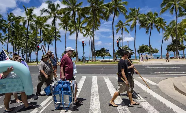 Members of Hawaii Firearms Coalition walk around Waikiki with their non-firearm weapons on Saturday, June 22, 2024, in Honolulu, Hawaii. (AP Photo/Mengshin Lin)