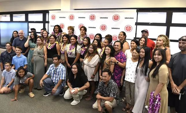 Lahainaluna High School 2024 graduates pose with family members during a scholarship presentation in the school's library Wednesday, July 31, 2024, in Lahaina, Hawaii. (AP Photo/Matthew Thayer)