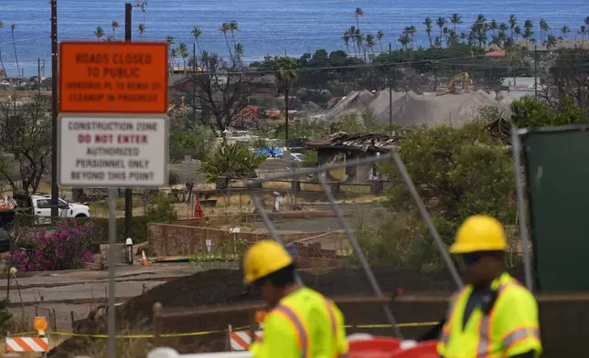 Crews work to clean debris and repave roads, Saturday, July 6, 2024, in Lahaina, Hawaii. The parties in lawsuits seeking damages for last year’s Maui wildfires have reached a $4 billion global settlement, a court filing said Friday, Aug. 2. The agreement comes nearly one year after the deadliest U.S. wildfire in more than a century killed 102 people and destroyed the historic downtown area of Lahaina on Maui. The Aug. 8, 2023, wildfire burned thousands of homes and displaced 12,000 people. (AP Photo/Lindsey Wasson)