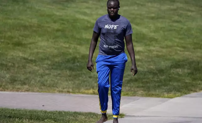 Ronald Okee, of Des Moines, Iowa, walks barefoot along the asphalt trail as the heat index tops 100 degrees at Gray's Lake Park, Monday, Aug. 26, 2024, in Des Moines, Iowa. (AP Photo/Charlie Neibergall)