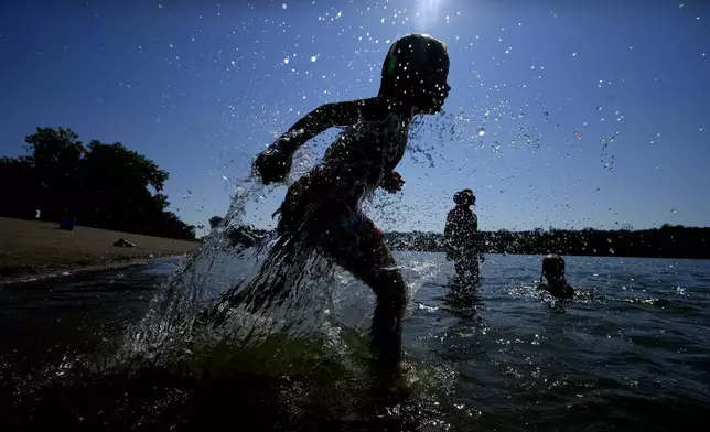 Judah Boyle, of Des Moines, Iowa, splashes water as he runs on the beach at Gray's Lake Park, Monday, Aug. 26, 2024, in Des Moines, Iowa. (AP Photo/Charlie Neibergall)