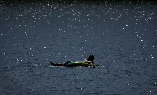 A tuber floats in the lake at Gray's Lake Park as the heat index tops 100 degrees, Monday, Aug. 26, 2024, in Des Moines, Iowa. (AP Photo/Charlie Neibergall)