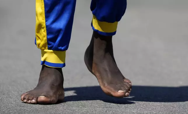 Ronald Okee, of Des Moines, Iowa, walks barefoot along the asphalt trail as the heat index tops 100 degrees at Gray's Lake Park, Monday, Aug. 26, 2024, in Des Moines, Iowa. (AP Photo/Charlie Neibergall)