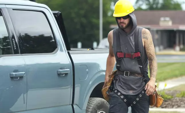 Construction worker walks past a residential building site during hot weather in Wheeling, Ill., Tuesday, Aug. 27, 2024. (AP Photo/Nam Y. Huh)